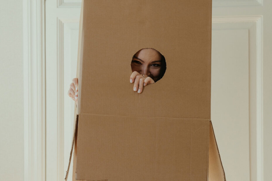 Woman stuck in a box, but peeking out with awareness.