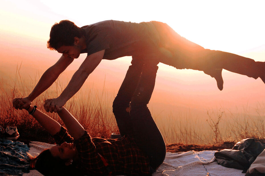 Grownups enjoying the growth that comes from play - woman holding man in airplane flying position with her feet