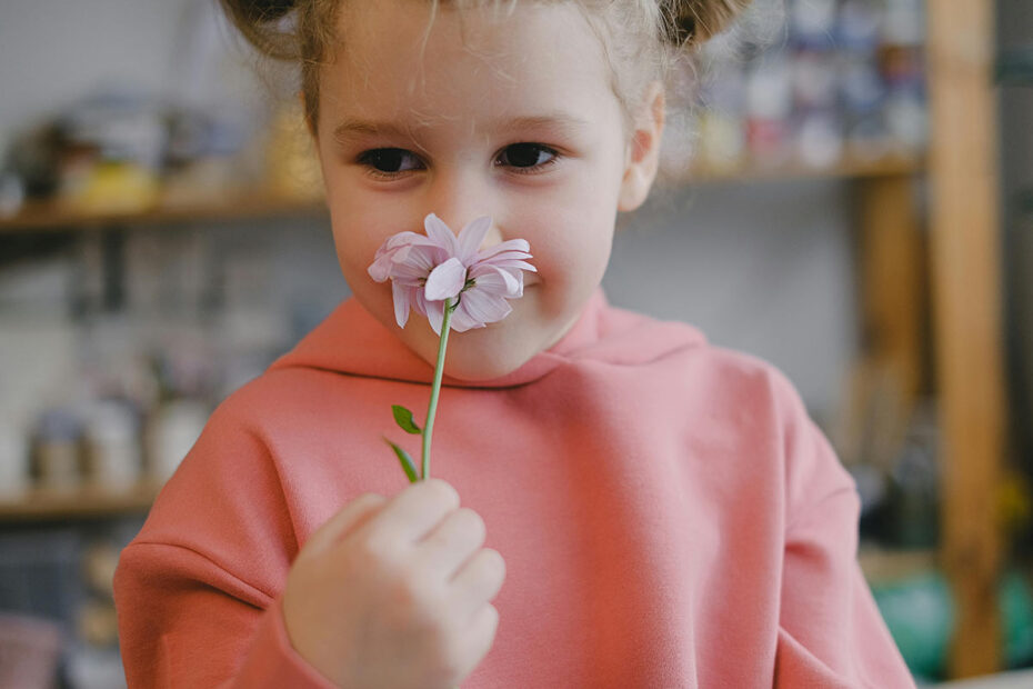 A young girl smells a flower with gratitude and delight