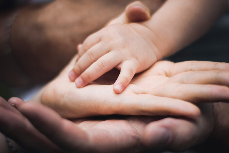 A child's hand in their parents', representing eudaimonic well-being